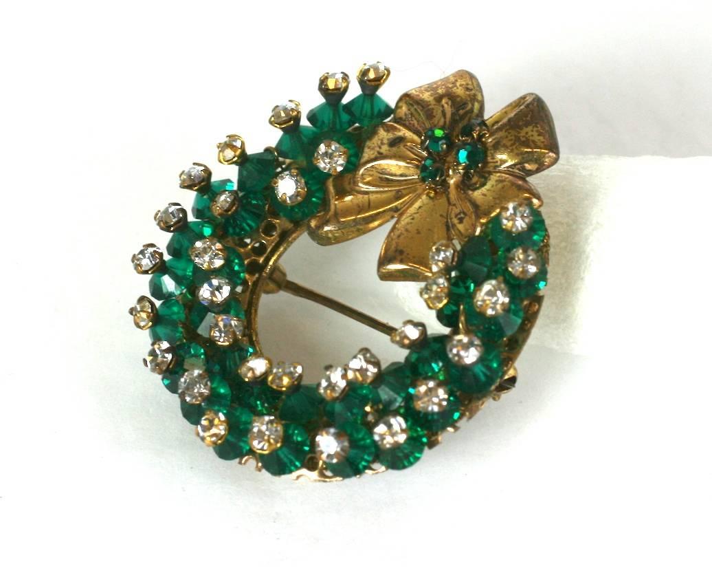 Miriam Haskell rare Holiday Christmas wreath brooch. The circular wreath and applied holiday bow are hand sewn with deep emerald Swarovski faceted crystals and rose monte crystals. Set in signature Russian gilt filigree. 1950's USA. 
Excellent