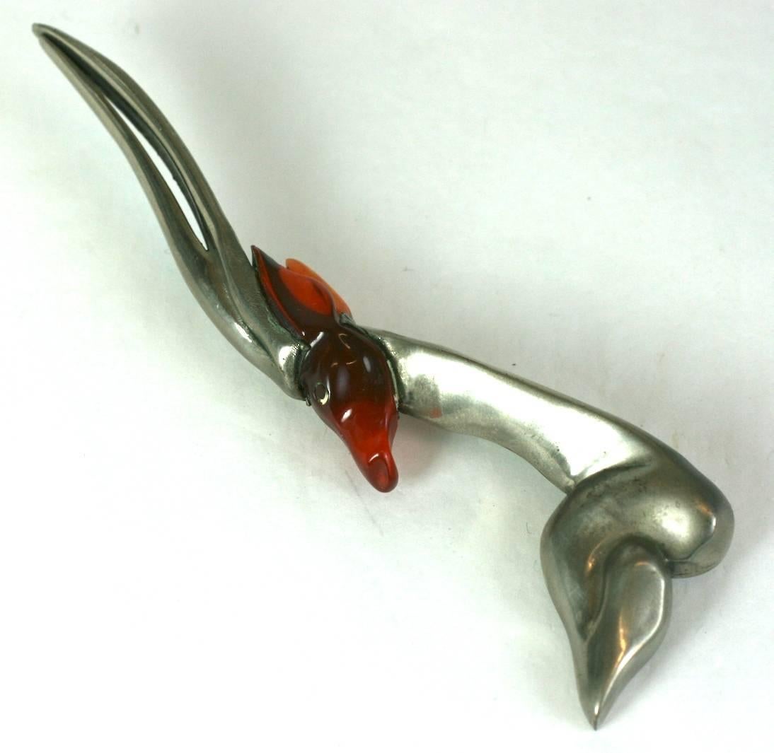 Unusual Art Deco Gazelle brooch of tortoise bakelite clad with silver metal. 
Artisans in the period found novel ways to treat hand carved bakelite whimsies like this. Covering (cladding), using hot metal over the bakelite was one process in which