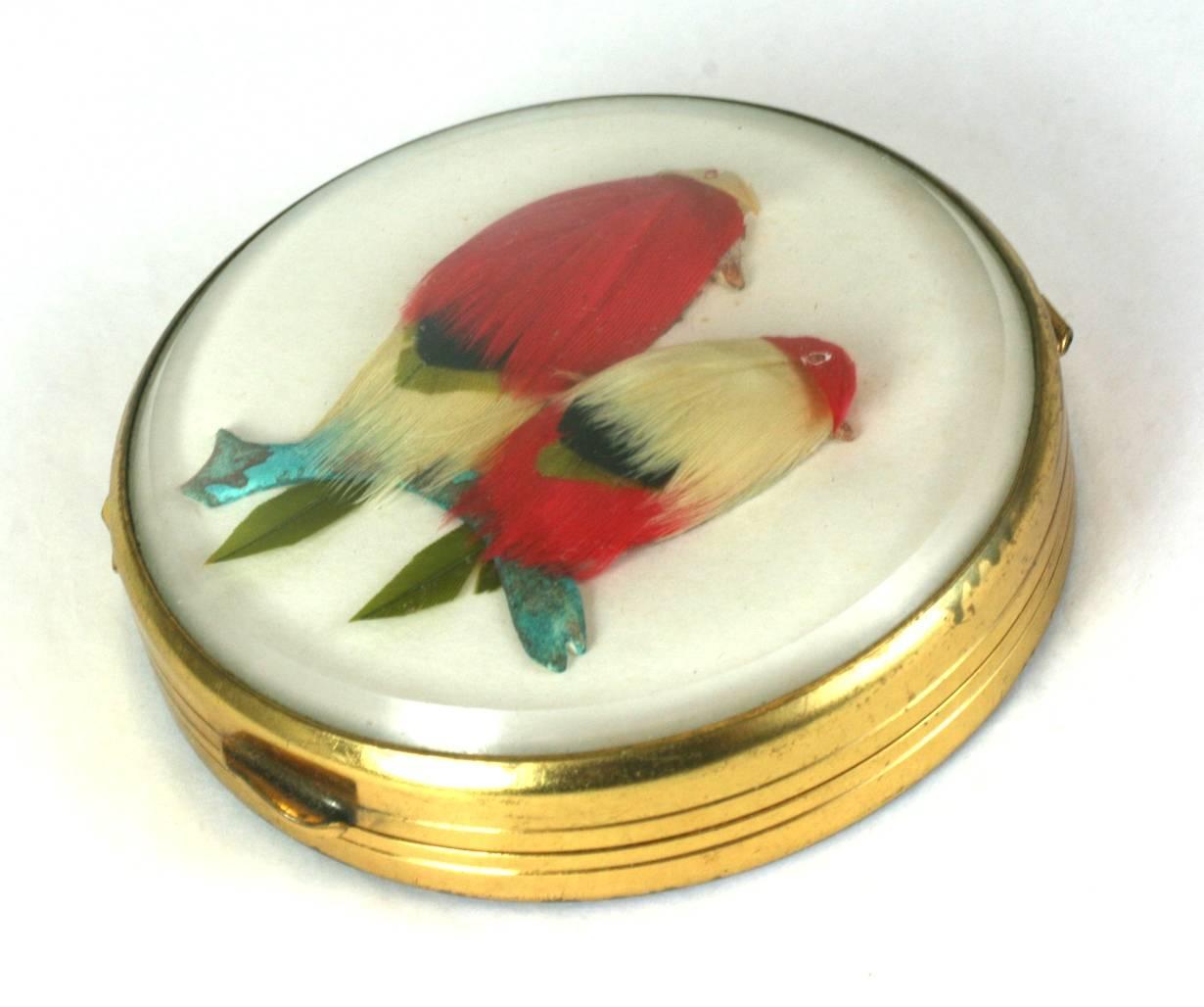 Charming and unusual French Feathered Bird Compact from the 1950's.  A pair of charming feathered birds are perched on a patinaed branch and set under a glass dome with a mirrored interior, powder screen and pad. The base is also glass so you can