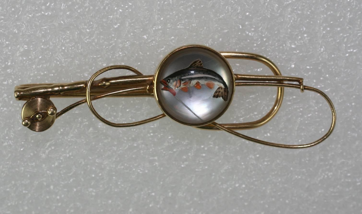 Art Deco Reverse Crystal Fishing themed Tie Clip from the 1930's. 
Super reverse carving of a salmon in mid flight with a line in its mouth under a rock crystal cabochon. A mother of pearl backing adds to a luminescent glow behind the