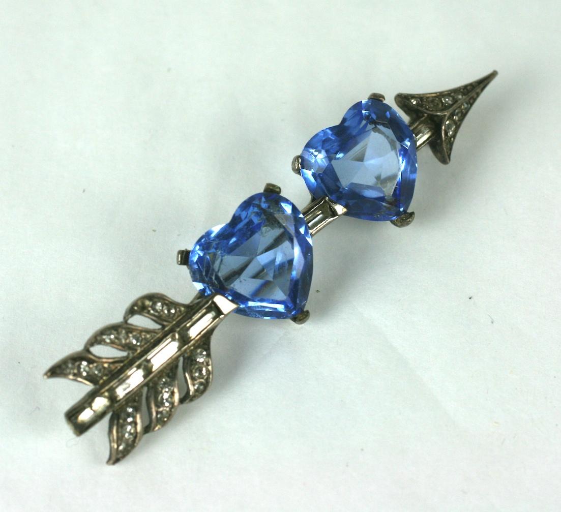 Rare Marcel Boucher Edwardian Revival double heart pierced arrow brooch. Of rhodium plated sterling silver, with vari size and shaped crystal pastes. Faux pale sapphire heart shape stones. 
Signed: MB phrygian cap, Des Pat'd, Sterling
Excellent