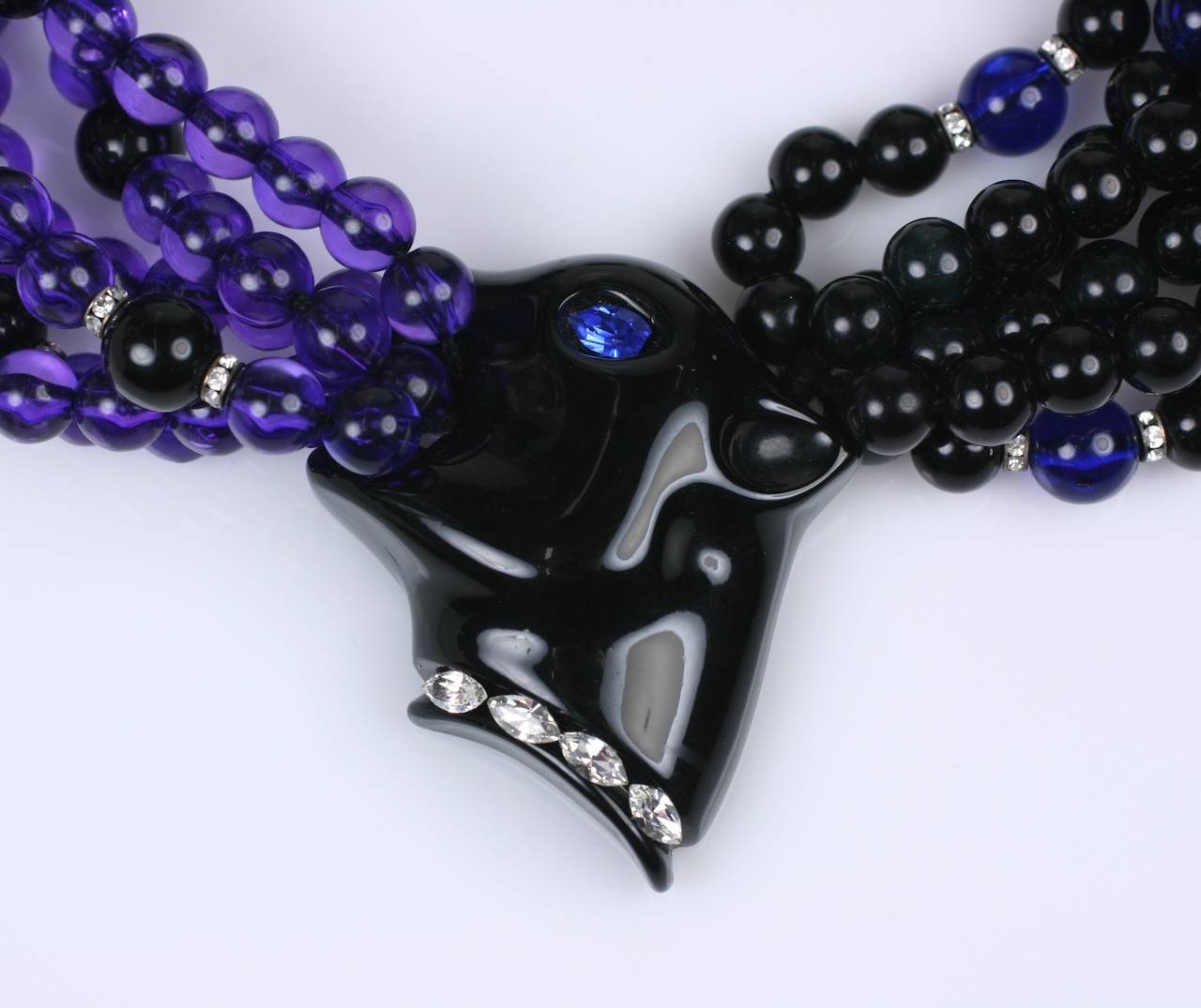Italian Bakelite Panther Necklace, 6 strands with pave rondels accents. One set of beads are black and the other are violet. The panther head is set with pave marquise stone collar and a faux sapphire eye. 
Italian plastics are known to be the