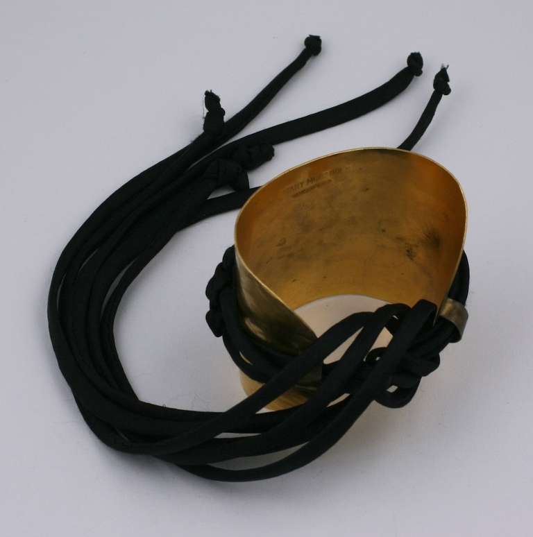 Mary McFadden's dramatic hammered gilt cuff with black silk Chinese knot decoration. An interesting companion piece for her Fortuny pleated gowns.  1980's USA. Signed. Excellent condition.