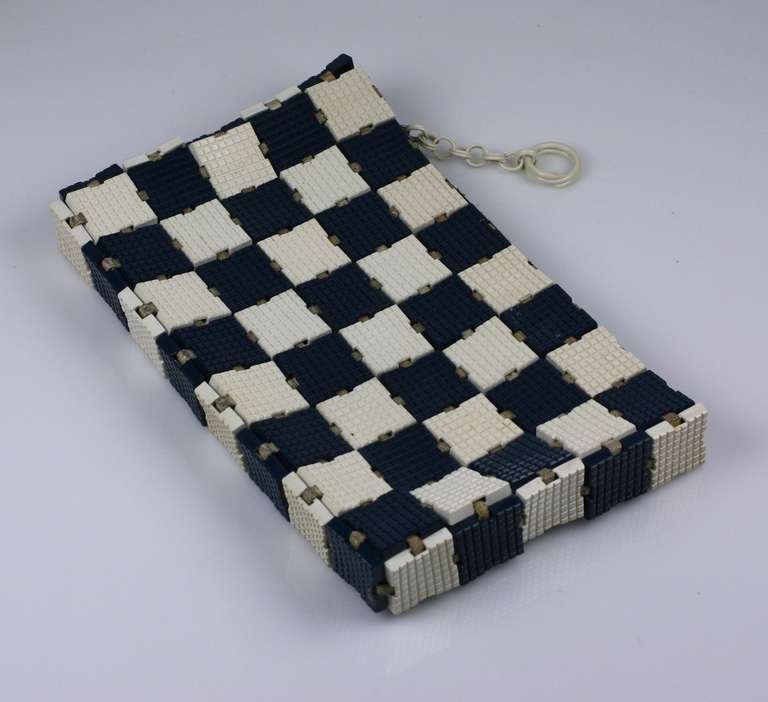 Art Deco clutch composed of plastic tiles in navy and white checkerboard. Tiles are woven onto leather bands so the bag is flexible. A zipper closes the top. 
1930's USA. Very Good condition.