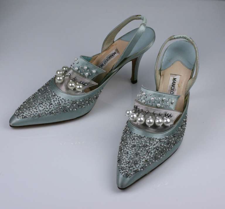 Lovely regal pale blue satin embroidered and beaded evening slippers by Manolo Blahnik.  The satin is embroidered with silver seed beads, rhinestones and pearls. There is also a faux pearl crown motif dangling upside down from the silver satin tier.