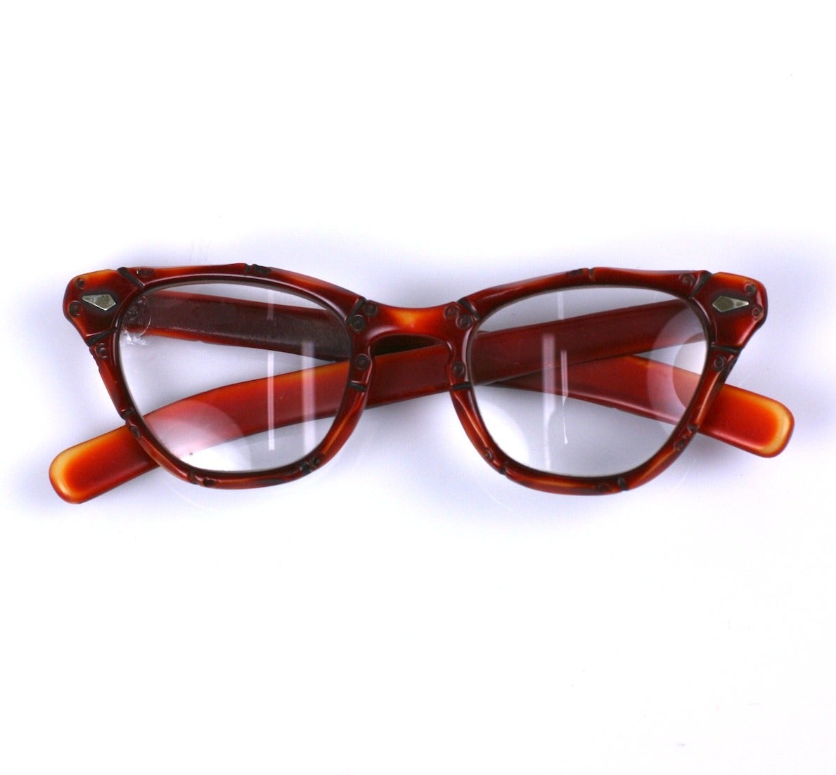 Art Deco hand carved bakelite eyeglass frames with wonderful patina. Cream bakelite with reddish-orange patination creates the look of bamboo with carved segmentation.
These charming frames currently have prescription lenses (one chipped) which