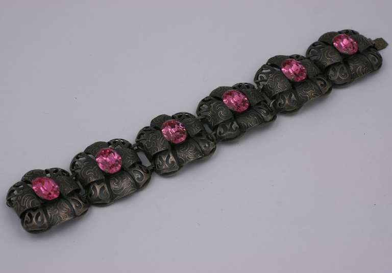 Art Deco bracelet made in the Arts and Crafts style in antique silvered metal with large oval pink crystals. An amalgam of the hammered lines of the Jugenstil metalwork with the addition of vibrant color. Excellent condition. 7.5 x 1.25