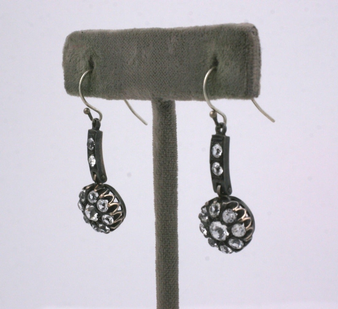 Antique paste articulated earrings are set in sterling silver from the late 19th Century. The pastes on the cluster drop are set into crown settings and are suspended from a paste set bar. 1