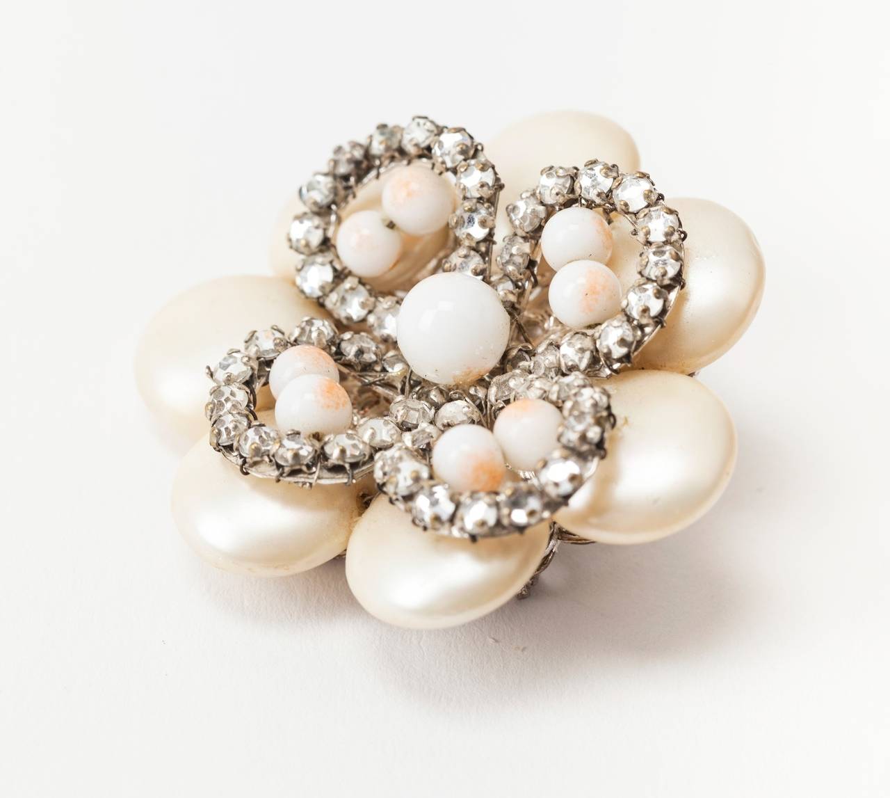 Miriam Haskell Floral Brooch decorated with crystal rose montees and faux angel skin coral pate de verre beads. The larger petals of rare iridized finished faux pearls. The brooch is set onto a silver gilt signature filigree base. 
1950's USA. 