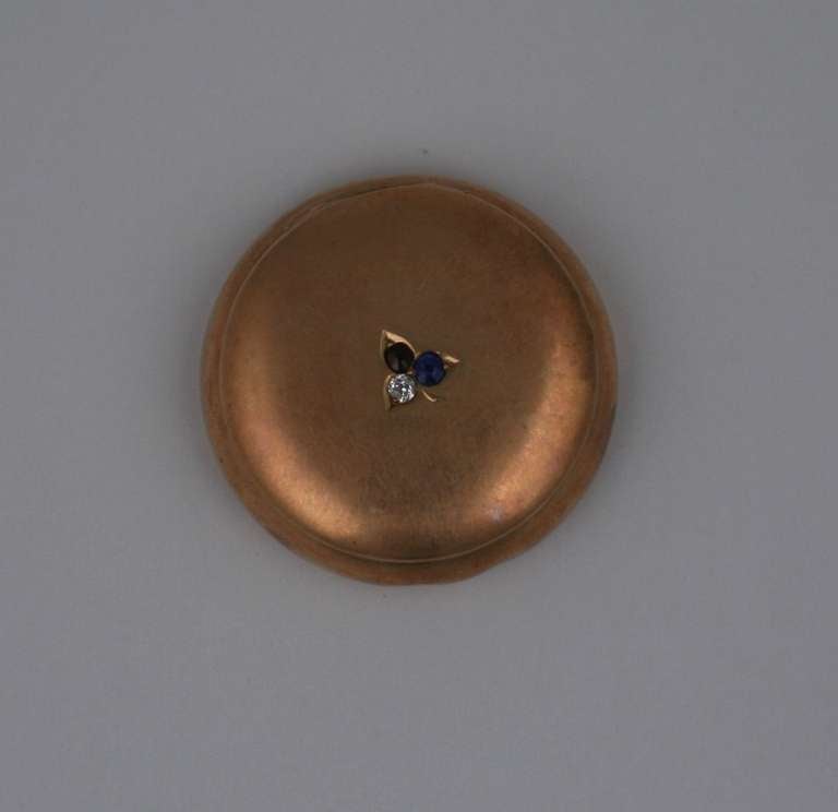 Pink 14k gold and gem set pillbox from the late 19th Century. Cover is set with a single diamond, ruby and sapphire. Conjoined Victorian monogram on base. 1 3/8