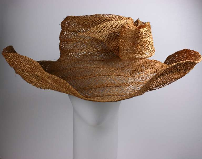 Massive handwoven openwork straw hat with large bow. This scale of this picture hat is incredibly striking and editorial. Insane and rumpled in a good way. 
Interior 21-22". Brim 8", Crown 3". Italy 1980's. Excellent condition.