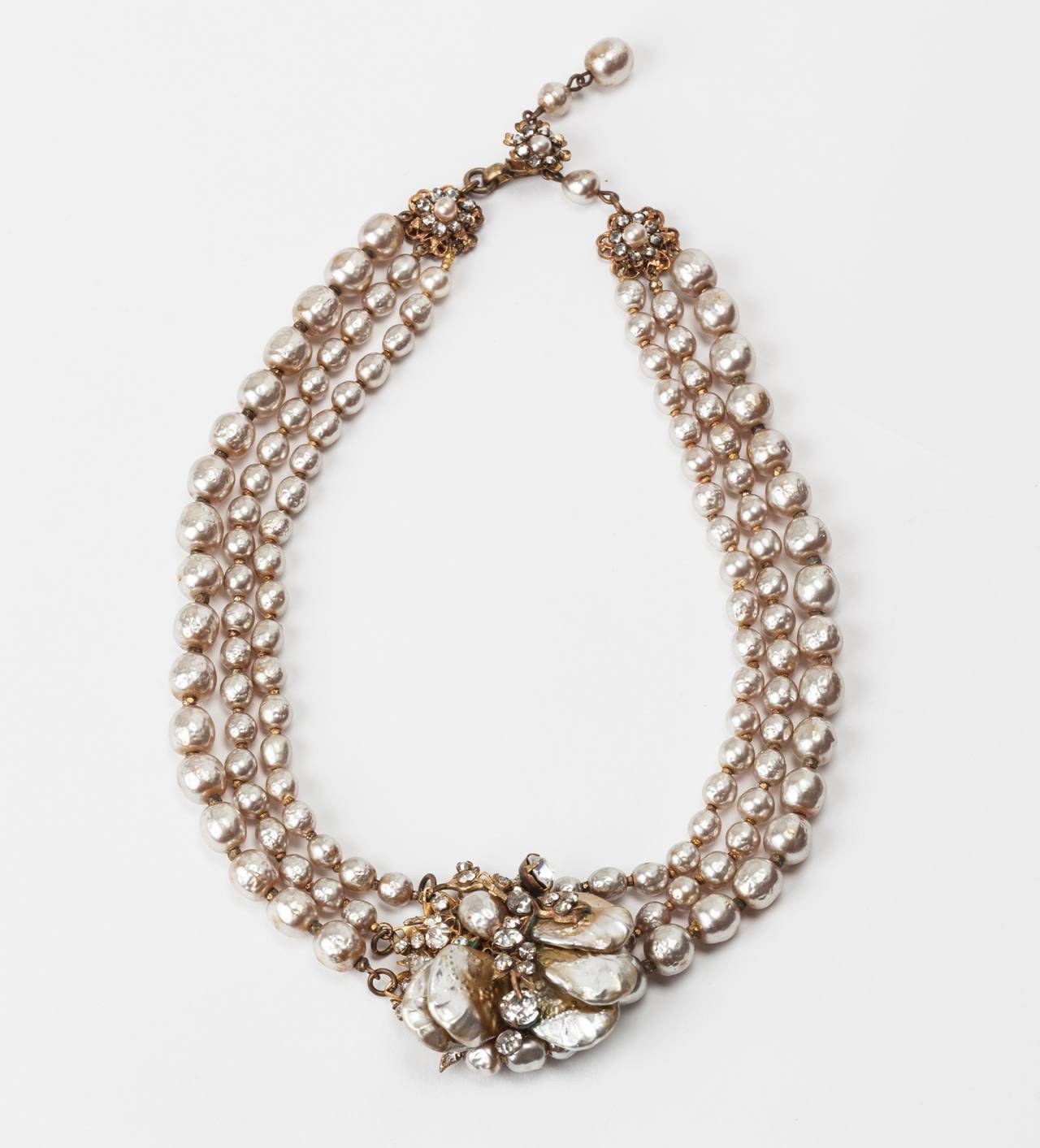 Miriam Haskell Classic three strand (three size) signature baroque faux pearl necklace. The center motif is made of Miriam Haskell's classic signature Russian gilt filigrees and crystal pastes. Vari sized baroque pearl petals with round and oval