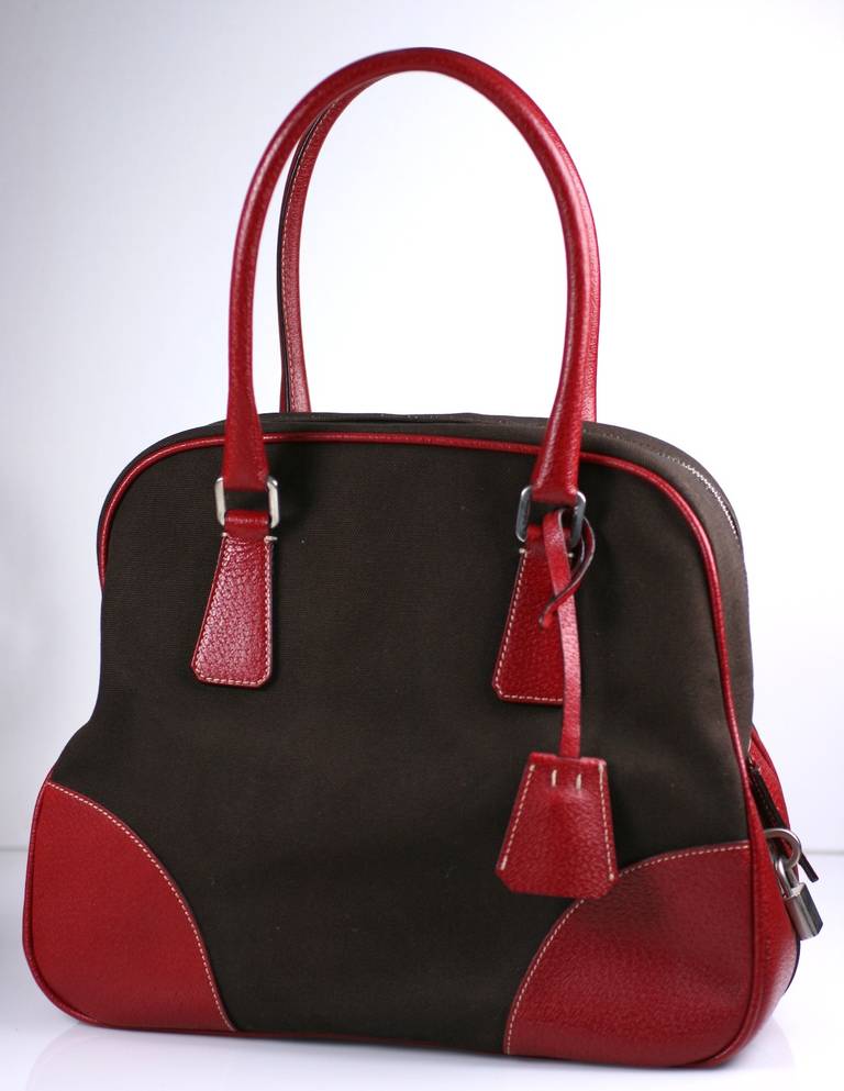 Miuccia Prada's elegant take on the American bowling bag rendered in red pebbled leather and brown cotton canvas. ID tag and lock included. Wonderful detailing. 12