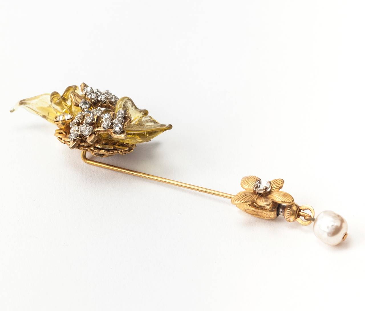 Miriam Haskell two part stickpin brooch. The head is set with carved citrine glass leaves and hand sewn rose montee crystals. The safety lock is set with signature flower and seed pearl drop. Excellent condition. 1940's USA. 
Length 3.50