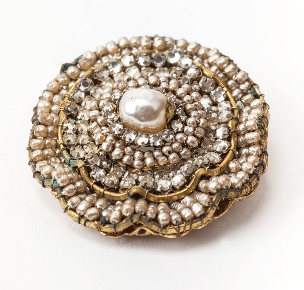 Miriam Haskell layered circular brooch of hand sewn faux baroque pearls and crystal rose montes. The stepped three dimensional brooch is centered by a large signature faux baroque pearl. The mountings are of signature Russian gilt filigrees. 1940's