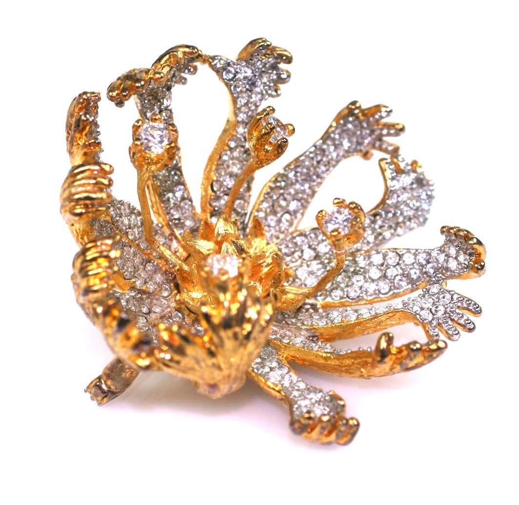 Salvador Dali Surrealist Flower Brooch with petals made of pave human arms and hands. 4 larger crystals are hand held from the center cluster of gilt petals.  
Very dimensional with creepy hands going in various directions. Wonderfully subversive