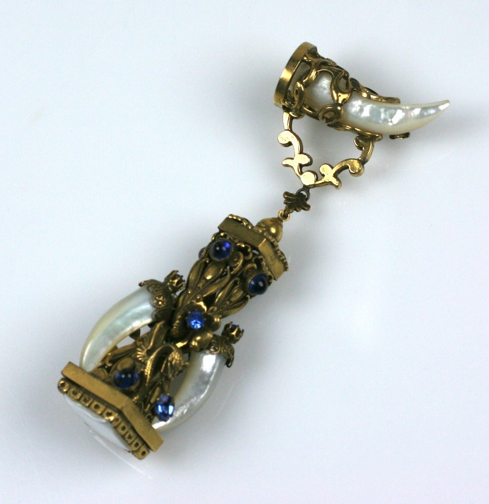 Unusually large fantasy brooch in the Victorian Revivalist taste made with mother of pearl tusks and faux sapphire pastes. Unusual metal filigree mounts decorated with dragons and swirled ribbon decoration. A square cut mother of pearl stone sits at