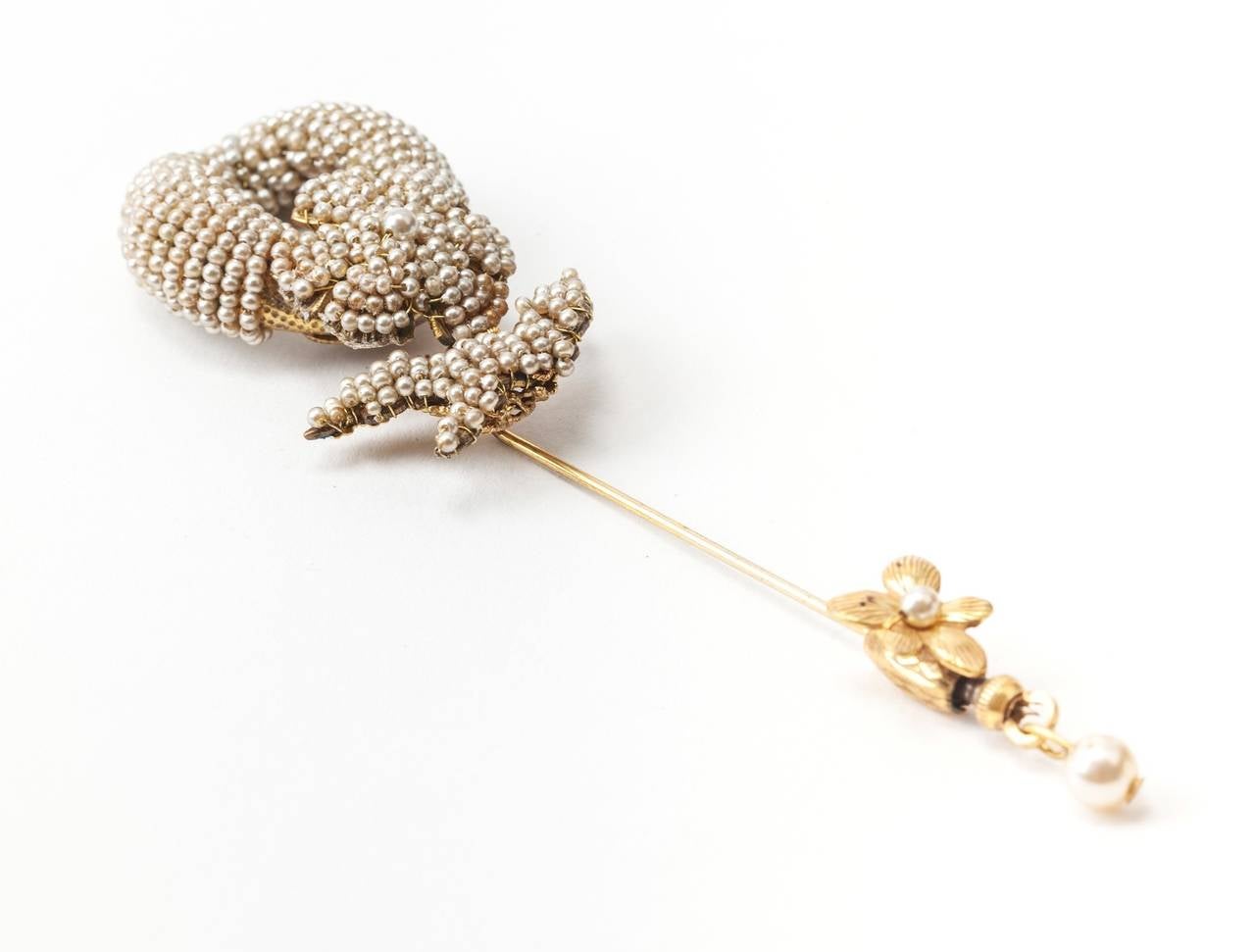Miriam Haskell's two part stick pin brooch. Rare and unusually long stickpin brooch of Russian Gilt metal with embroidered intricate bead work.
The oval ring and flori form signature filigrees are hand sewn with faux micro seed pearls. Gilt floral