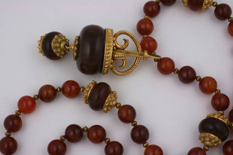 Large faux amber bead necklace in bakelite by Kenneth Jay Lane in the ethnic taste. Oversized beads are spaced with gold beads and a large drop with gilt cap hangs as a pendant. Imposing necklace with Moroccan overtones.  33