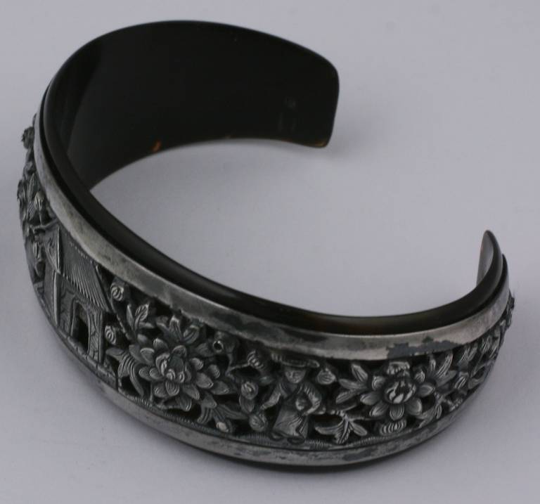 Antique Chinese bracelet. A silver hand raised decorated band is bolted onto a tortoiseshell base. Motifs centers around a house bordered by floral blossoms. 1920's China. Excellent condition.  15.5 grams total. Domestic Sales ONLY.
6