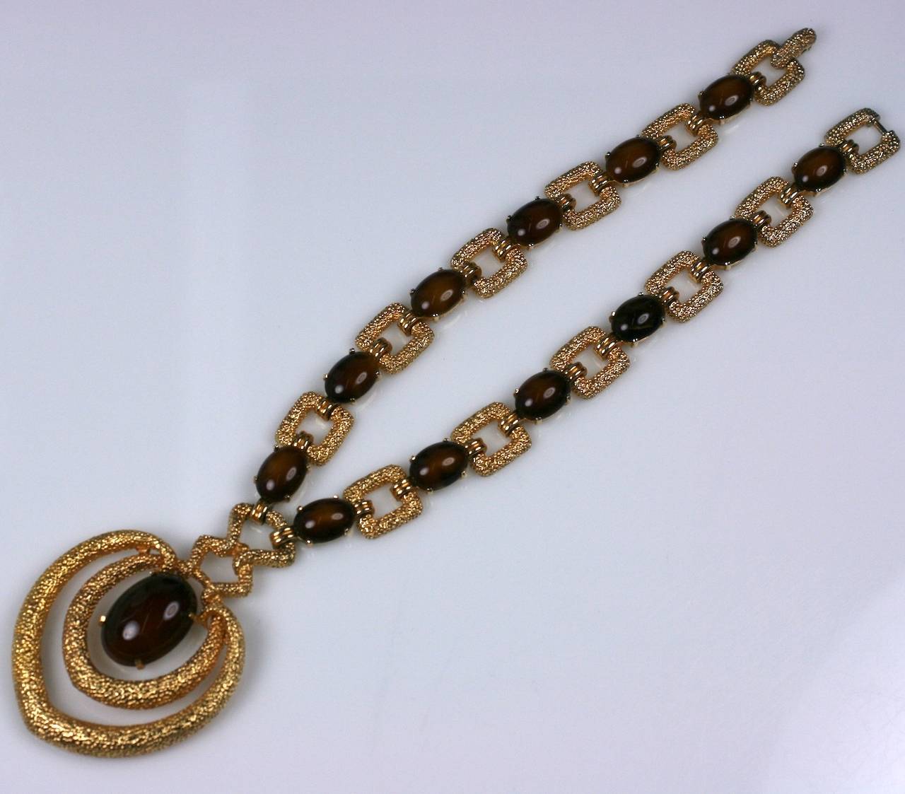 Attractive Webb Style Pendant by Joseph Mazer, NY. Textured gilt metal links are spaced with faux tiger eye cabochons which end in a large hooped, articulated pendant with central cab stone. Very Webb in feeling. 1970's USA.
Necklace 16