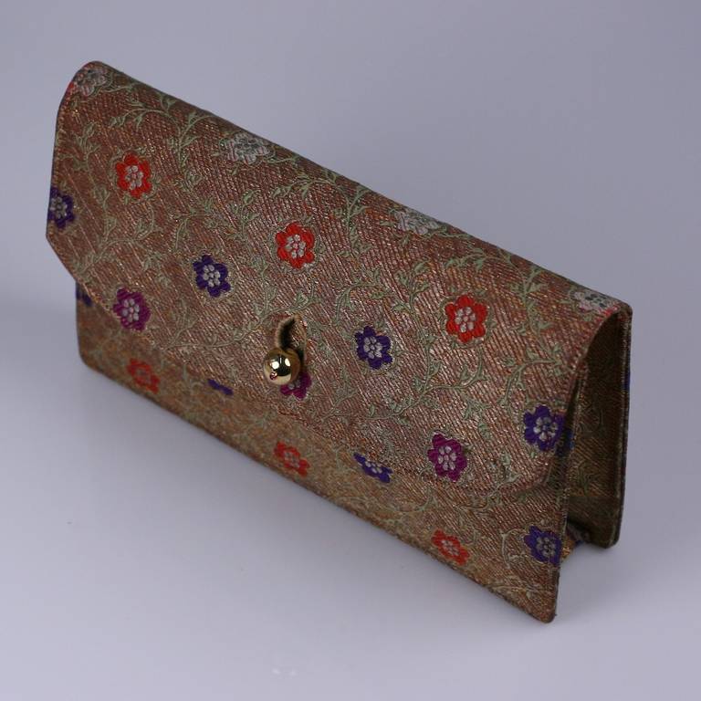 Elegant envelope clutch made antique metallic Indian textile with 14K gold ball and ruby clasp. Lined in peach silk satin with multiple compartments.  USA 1950's. 
Excellent condition. 9