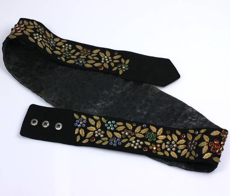 1930's Art Deco black suede belt with hundreds of collet set paste stones in multicolor palette with gilded leaves throughout. Wider in the front with snap closures in the back. Lovely handwork. Adjusts between 30-31