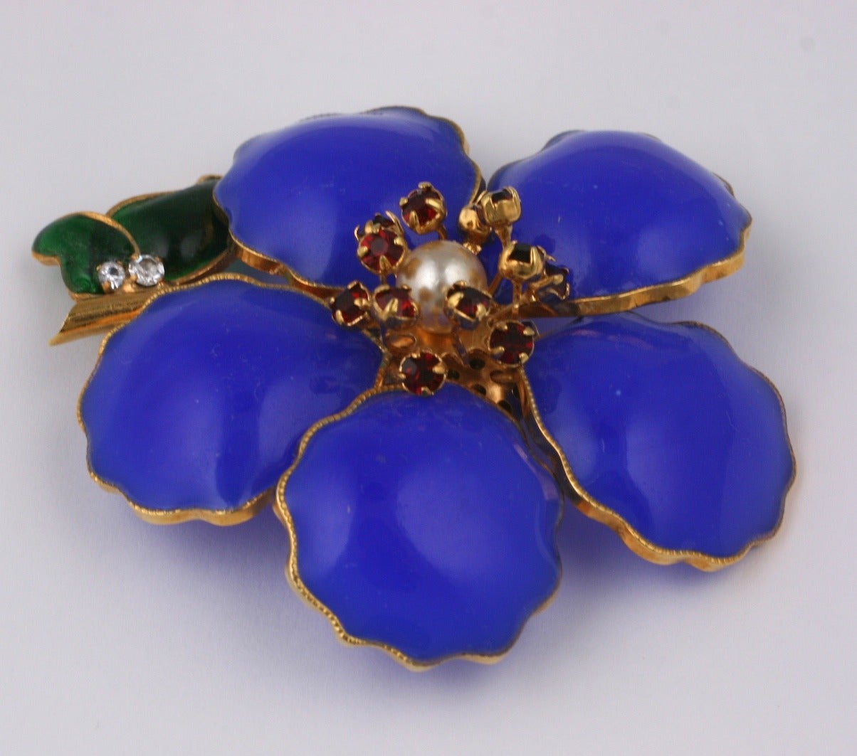 Chanel's poured glass  Camelia  brooch circa 1960's by Maison Gripoix. Bright lapis blue poured glass emamel petals with faux pearl, ruby strass center and emerald green glass leaves.
3 x 2.5