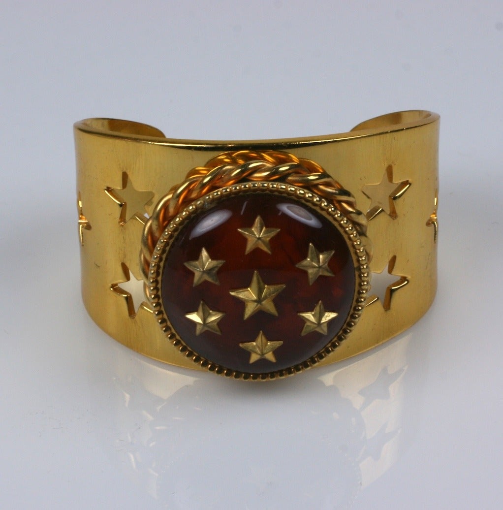 French compact bracelet from the 1950's. Tortoise bakelite covered compact is studded with gold stars and decorated with a gilded twisted wire bezel. Stars are also punched out of the metal cuff base. Has original puff and mirror.
Signed Claudine