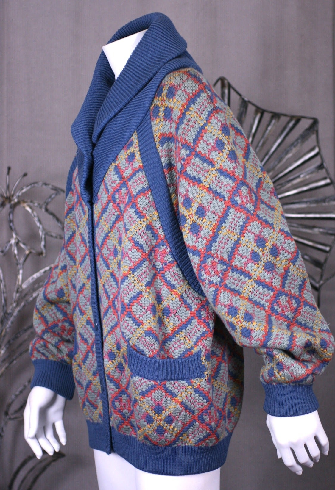Cardigan en laine argyle intarsia YSL Rive Gauche inséré avec des bandes et des poches en tricot côtelé bleu ardoise. Il y a un col châle en tricot côtelé bleu, une patte de boutonnage et des manches raglan profondes. france des années 1980.