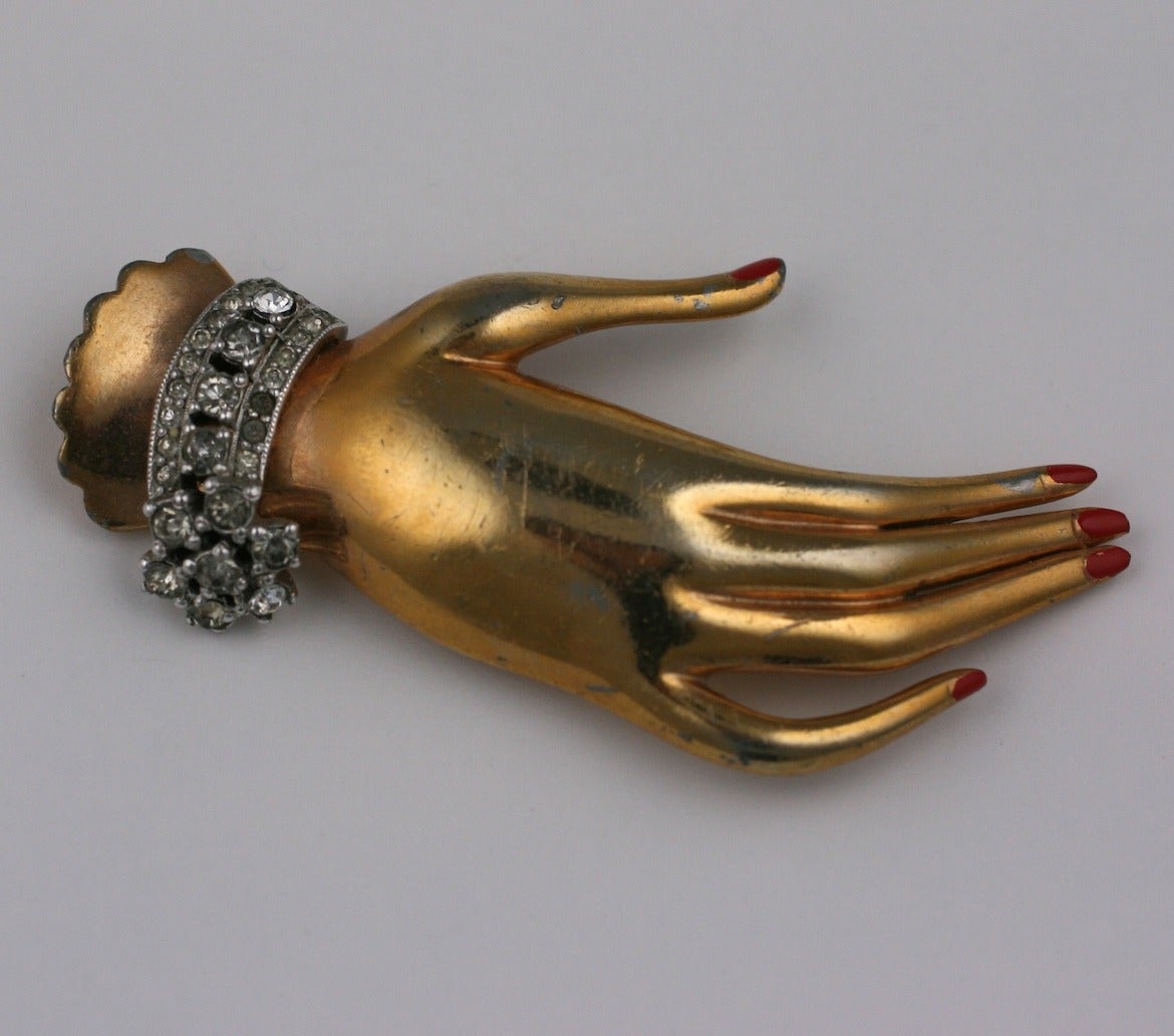 Kramer surreal retro gilt hand brooch sporting a miniature pave faux diamond cuff and cold enamelled red fingernails. 1940's USA.
Very Good condition.
L2.75