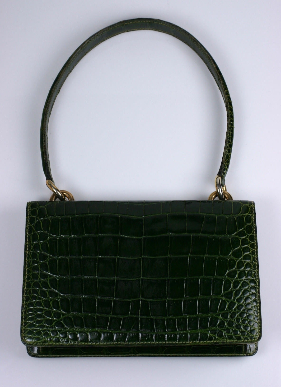 Elegant Lederer alligator bag in deep forest green with tapered and elongated handle which can be used over the shoulder as well. Very chic option with gilt barrel closure and bold gilt hoop metal fittings for handle. 
9