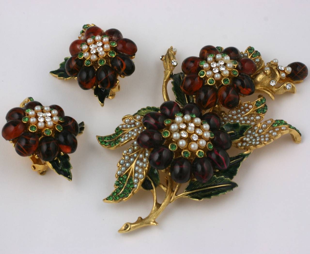Jose & Maria Barrera large spray of garnet toned cabochons with finely detailed pave seed pearl and green rhinestone pave work. Earrings have clip back fittings. 2010's. USA. Brooch 4