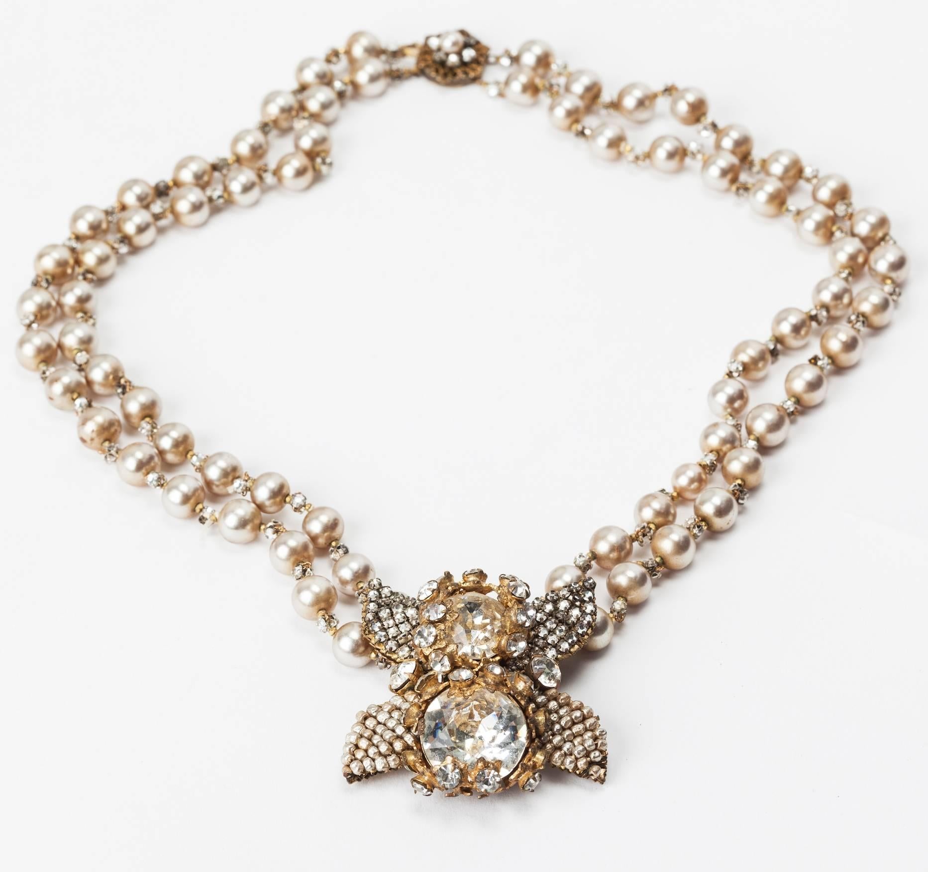 Superb Miriam Haskell two strand long faux pearl necklace. The signature graduated pearls spaced with back to back sewn rose monte crystals.The center focal pendant of two large faceted crystal paste stones set in paved Russian gilt filigrees. These
