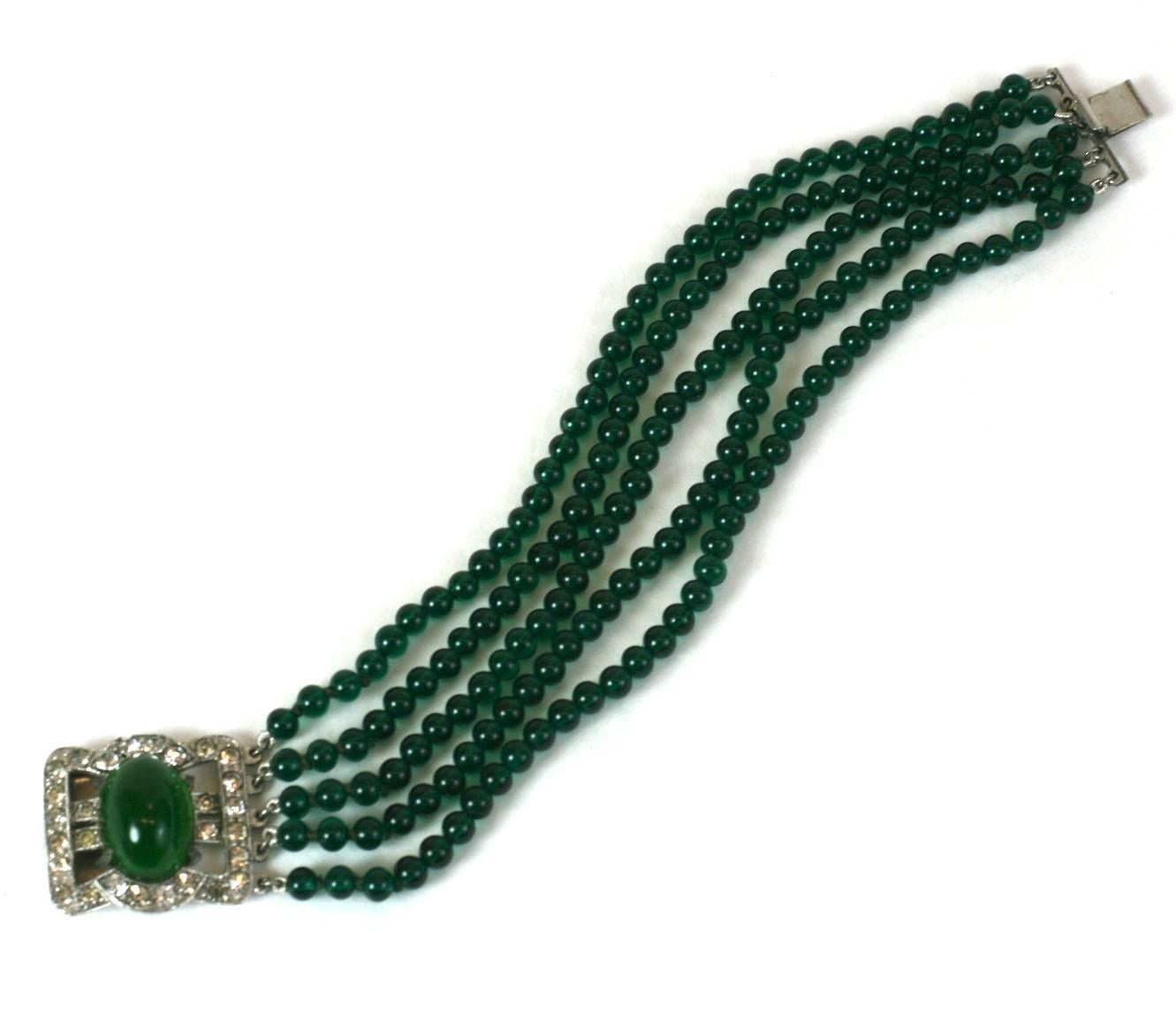 Art Deco Faux Emerald Bracelet with paste clasp centering large faux emerald cabochon within pave deco settings. The clasp is attached to a 5 strand emerald pate de verre bead bracelet.
1930's USA. 6.5