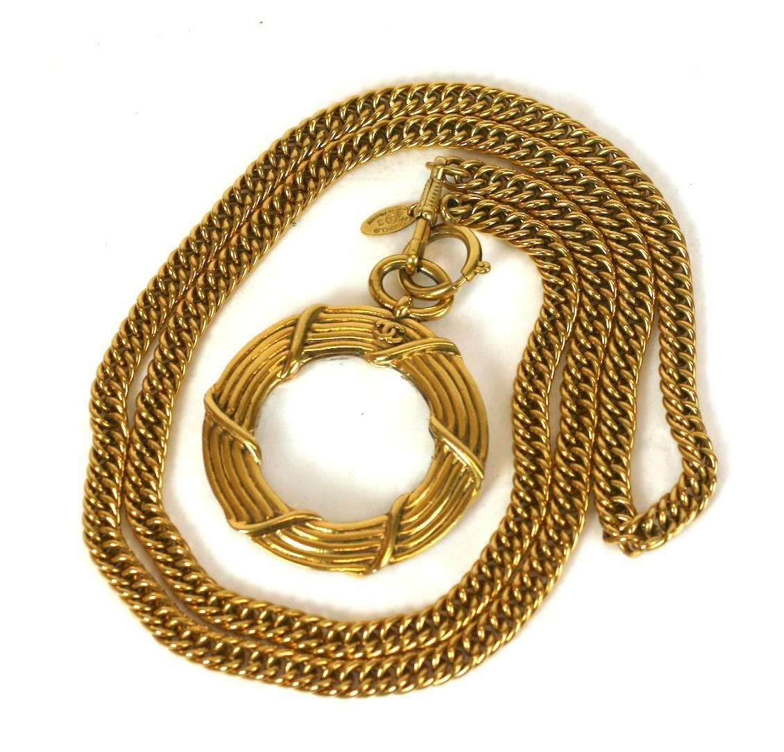 Iconic Chanel Magnifier Pendant Necklace in gilded bronze. Heavy chain with logo emblazoned on bezel of magnifier. Double clasps allow another pendant to be used with the same Chanel chain. 1980's France. Excellent condition.
