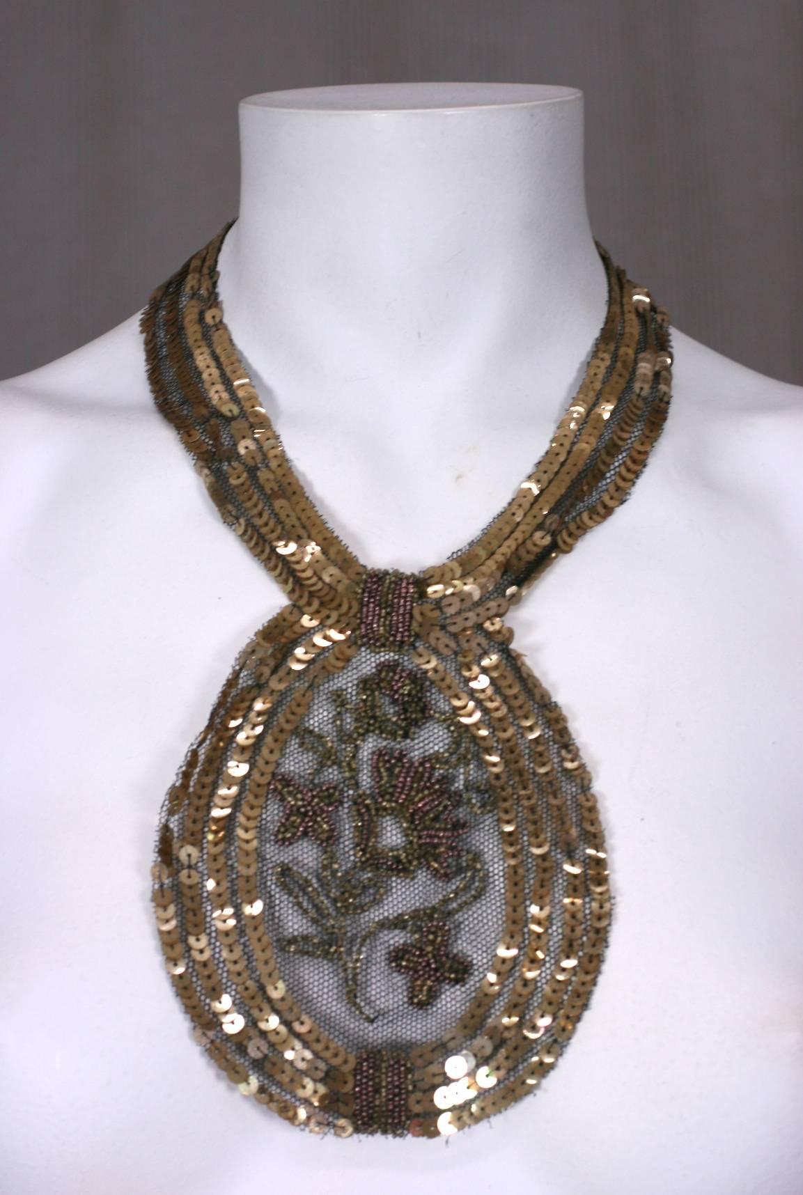 pièce de cou en paillettes et perles des années 1920, probablement née comme ornement de robe mais convertie en collier avec l'ajout d'un fermoir. Des paillettes et des perles dorées brodées à la main sont cousues sur une base de tulle noir. Délicat