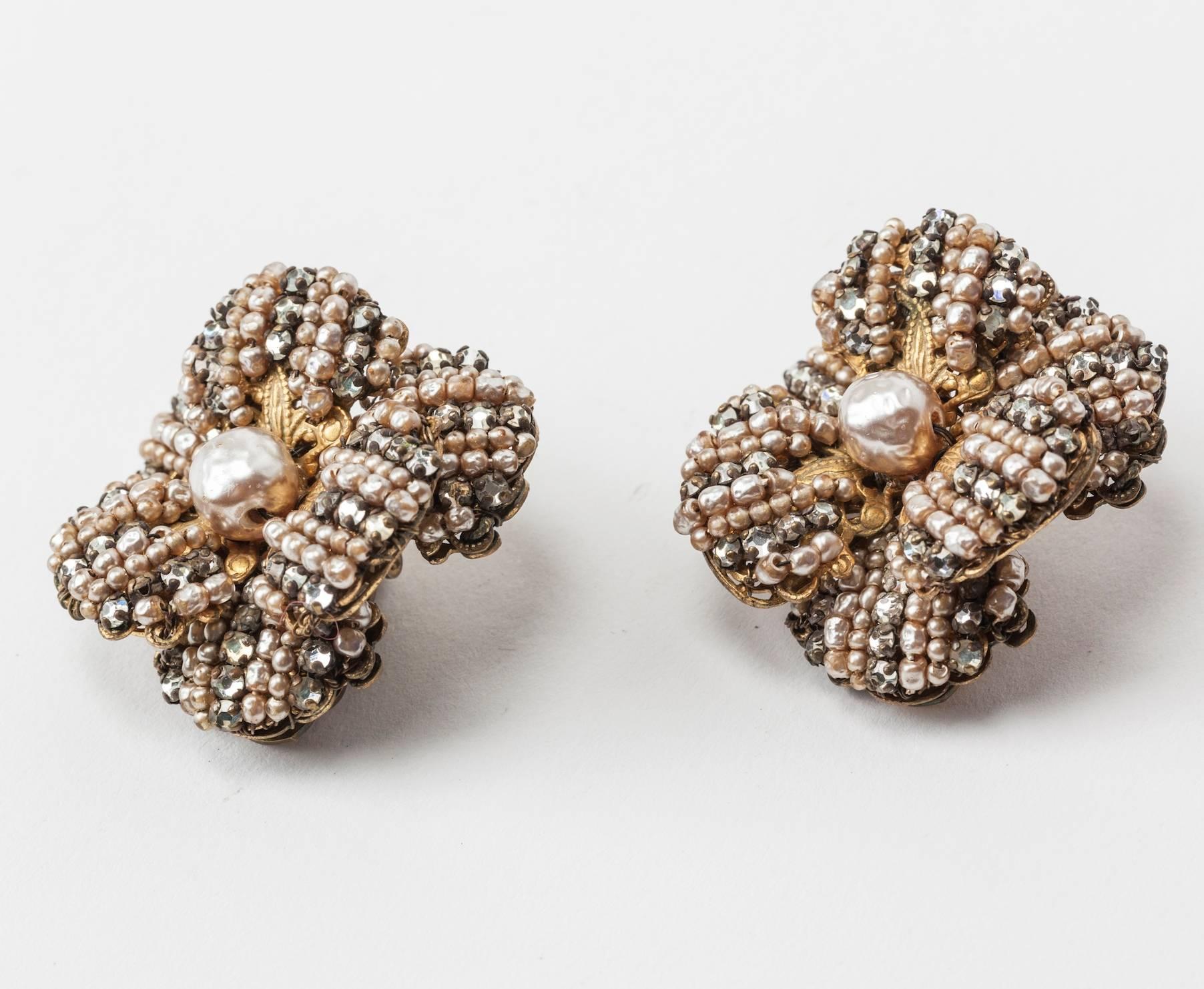 Miriam Haskell's large and dimensional floriform ear clips. Each is composed of six petals of gilt filigree, hand sewn with faux baroque seed pearls and crystal rose montes. Signature faux baroque pearl in center. Clip back fittings. Elegant