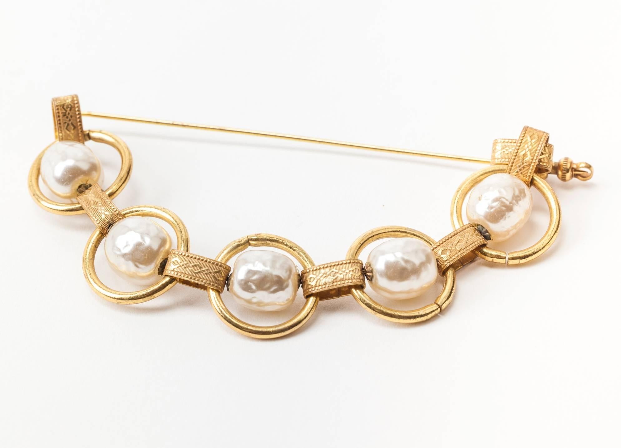 Insolite, grande broche à épingle à nourrice en deux parties, réalisée par Miriam Haskell, composée de grandes perles baroques caractéristiques et d'un maillon de chaîne doré russe élaboré. L'épingle disparaît dans le tissu lorsqu'elle est portée.