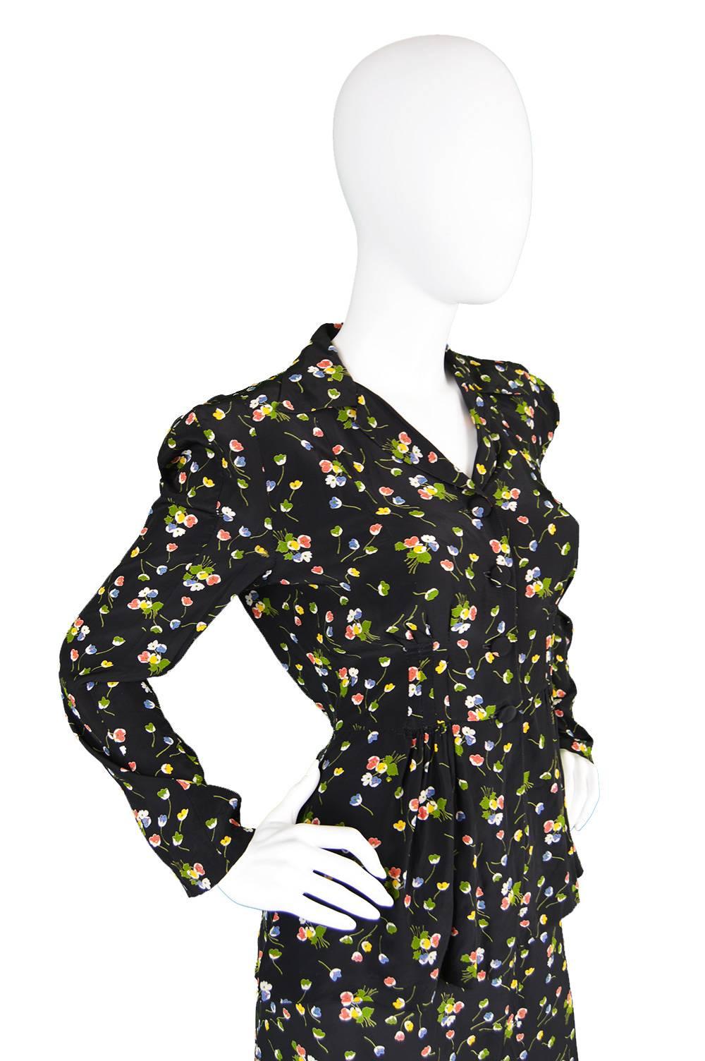 An incredible vintage women's two piece skirt suit from the 1970s by genius and highly collectible vintage British boutique designer, Jeff Banks. In a black, silky rayon fabric with a ditsy floral print and a 1940s inspired silhouette. The blouse