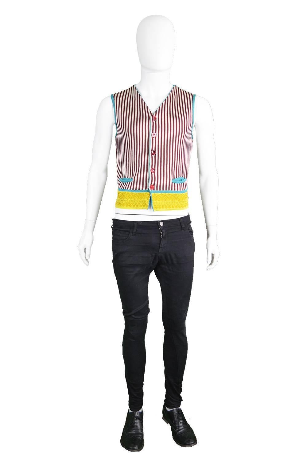 A fun and stylish men's knit waistcoat/ sweater vest from the 1990s by l'enfant terrible and genius designer, Jean Paul Gaultier. With vertical stripes down the front, a contrasting tribal knit pattern around the hem and a turquoise back and trim to