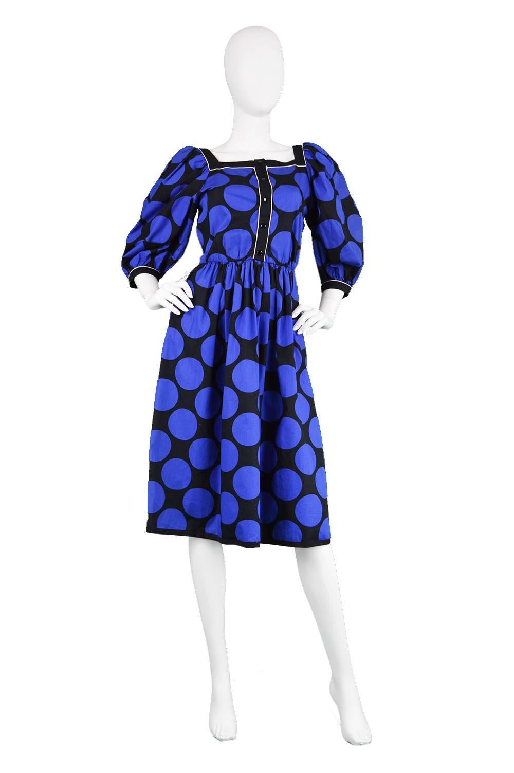 A chic vintage dress by highly regarded French designer, Louis Féraud from the 1980s, in a black and blue polka dot cotton fabric. The voluminous puff sleeves give a chic, high fashion look whilst the square neckline flaunts the wearer's