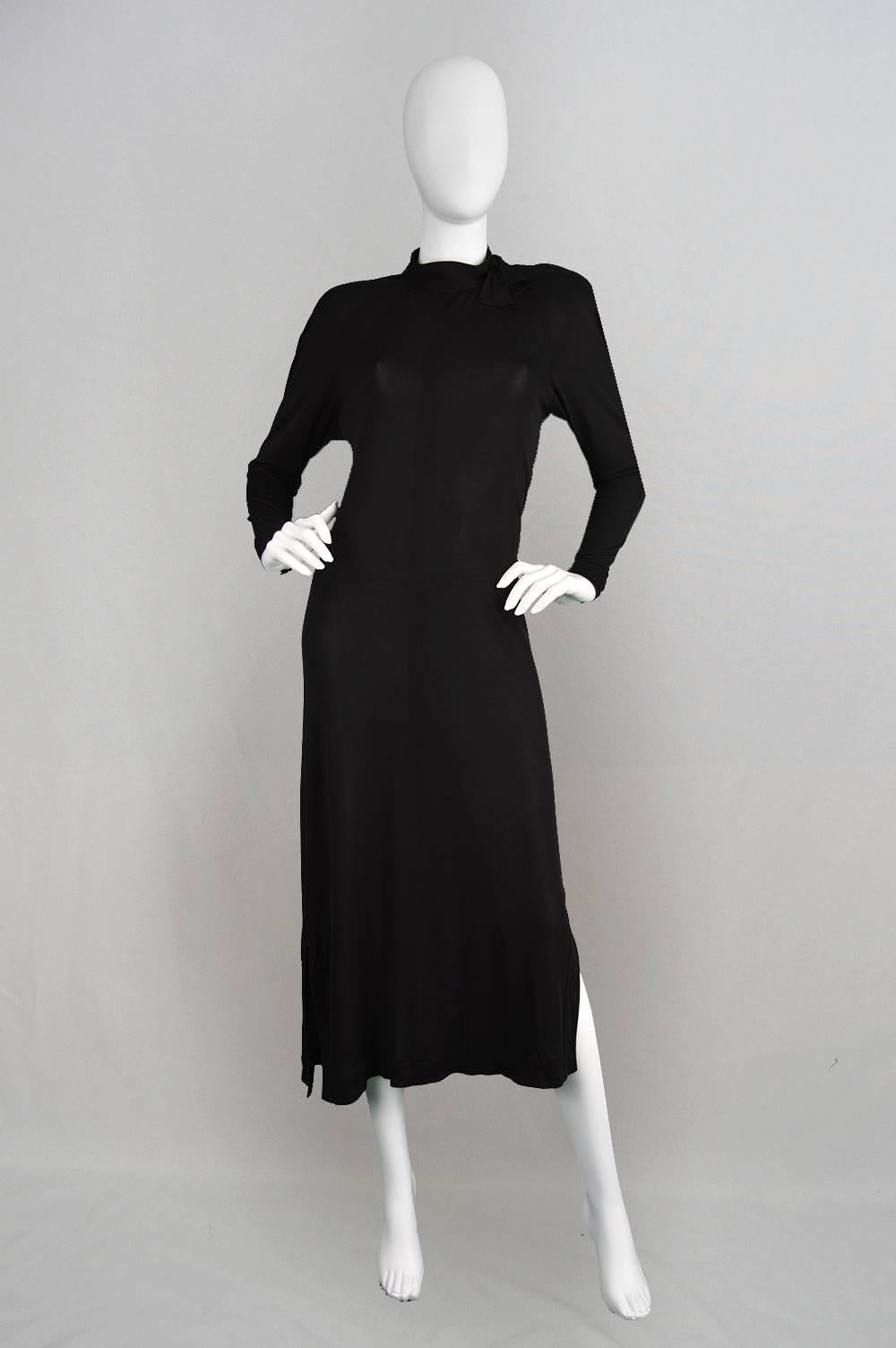 A timeless and elegant vintage Jean Muir dress from the 1980s with a high neck that has topstitched bowtie at the neck and lightly padded, darted shoulders that flow down to long slim, slightly dolman sleeves. The rayon jersey gives such amazing