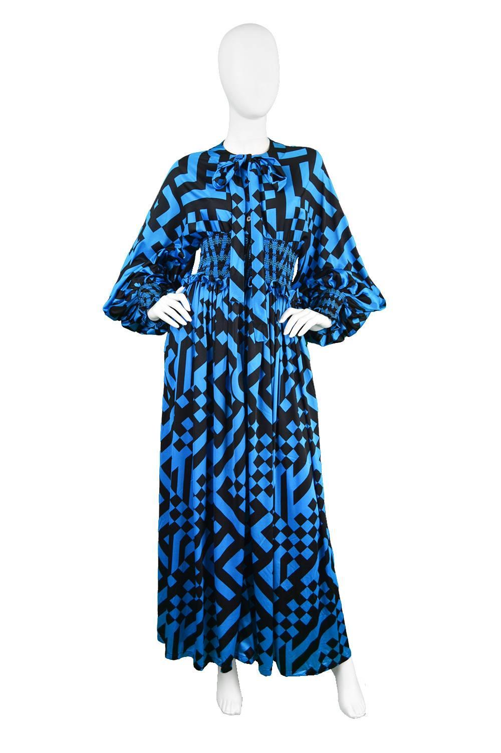 A stunning vintage maxi dress from the 1970s by genius vintage British designer, John Bates for Jean Varon, who was best known for his dramatic bohemian gowns in the 70s and this dress is a perfect example. In a blue synthetic jersey with a black op