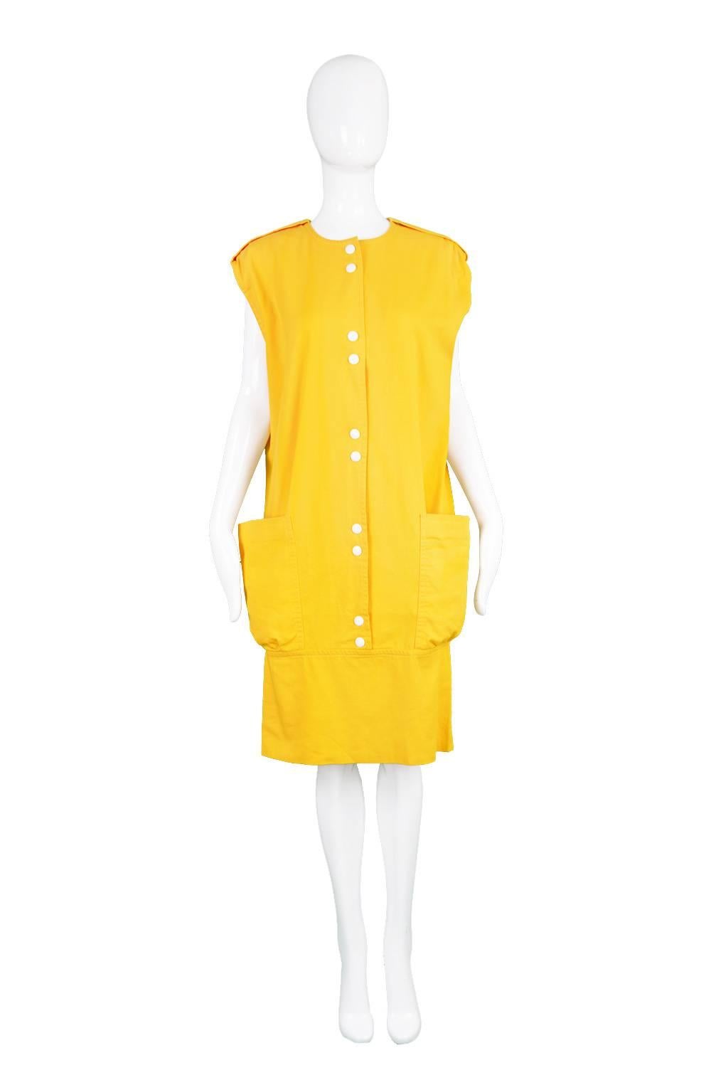 A fine vintage Pierre Cardin dress from the 1980s. In a mustard yellow cotton, an oversized fit on top with a band that pulls inwards at the top of the thighs and two huge, dramatic patch pockets - all create a retrospection of Cardin's earlier,