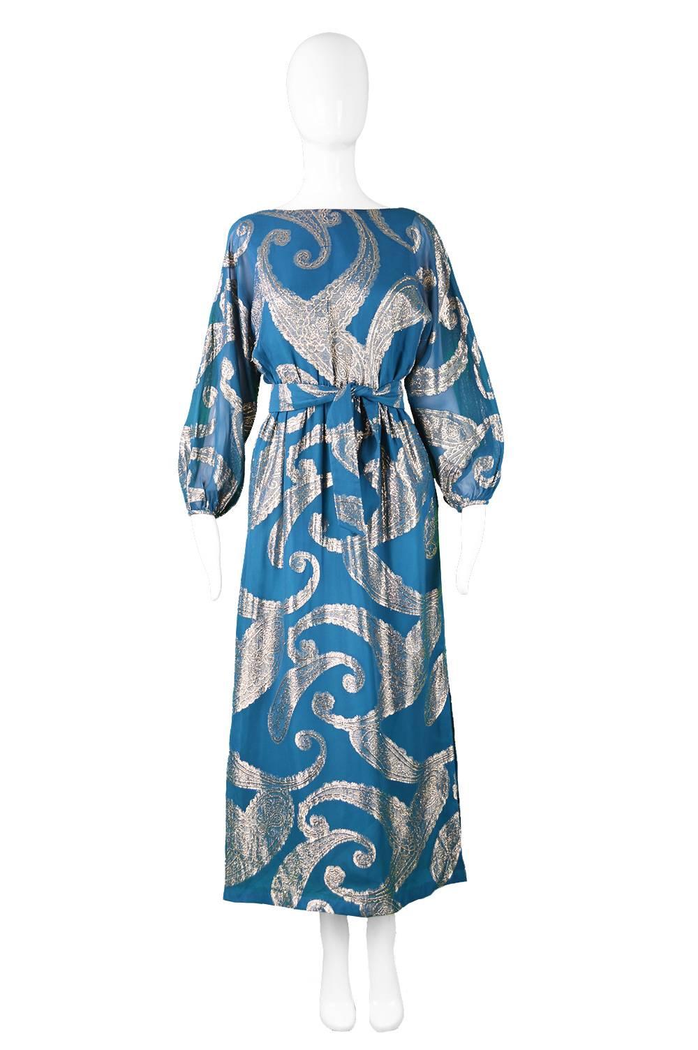 A beautiful vintage Victor Costa maxi dress from the early 70s in a dark teal chiffon with an Indian inspired gold paisley metallic lame brocade throughout. With sheer balloon sleeves, an elasticated waist and a half belt creating a feminine,