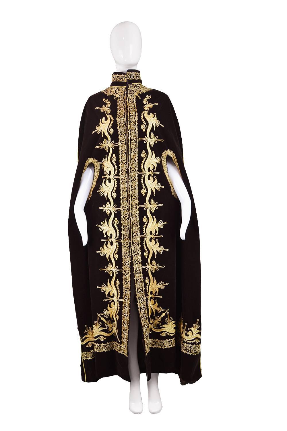 A dramatic women's vintage maxi cloak from the 70s in a brown short-pile velvet with intricate gold embroidery creating a hippy or bohemian luxe aesthetic. With poppers to fasten the front this looks stunning worn like an opera coat over an evening
