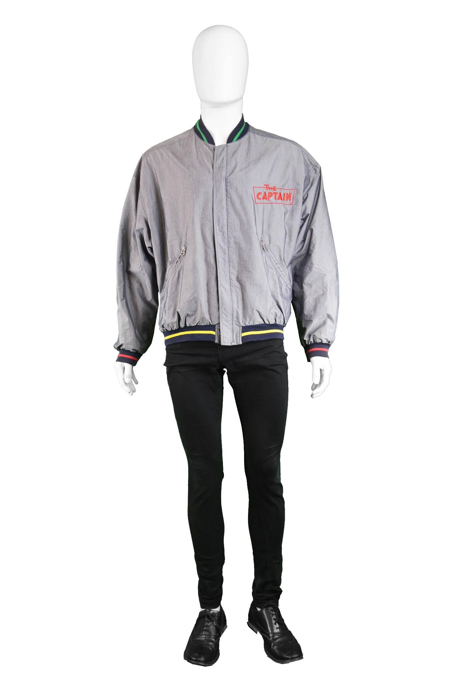 An awesome vintage mens or unisex bomber jacket from the 90s by JC de Castelbajac in a lightweight grey fabric with subtle sheen and a red stripe on the cuffs, yellow on the hem and green on the collar for a fun, whimsical look that Castelbajac was