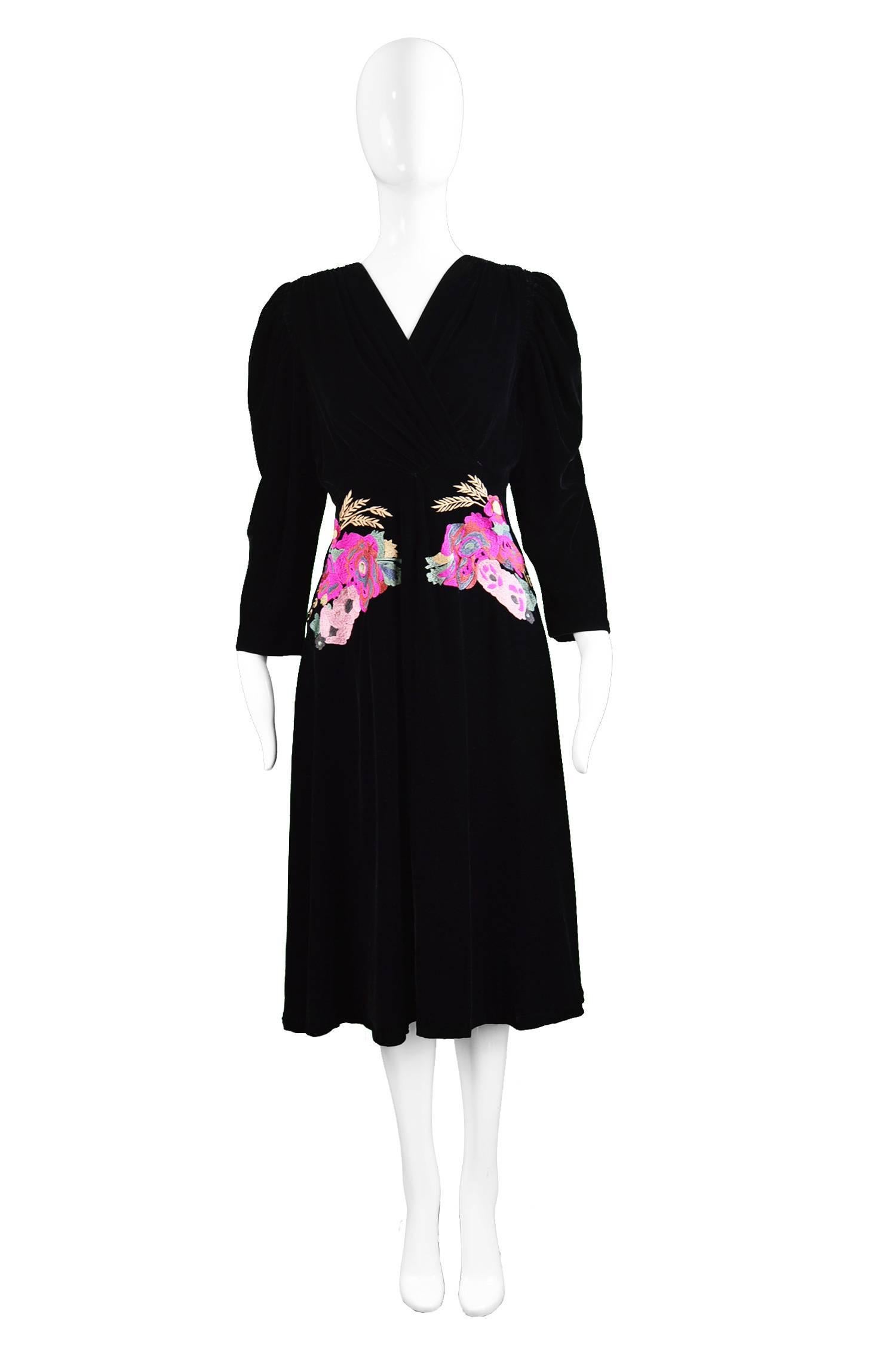 A stunning Kenzo evening dress in a luxurious black silk & rayon velvet. The shoulders have soft pleats at the front and on the sleeves which creates draping and a faux wrap style effect that flatters the bust. To the front of the dress are two