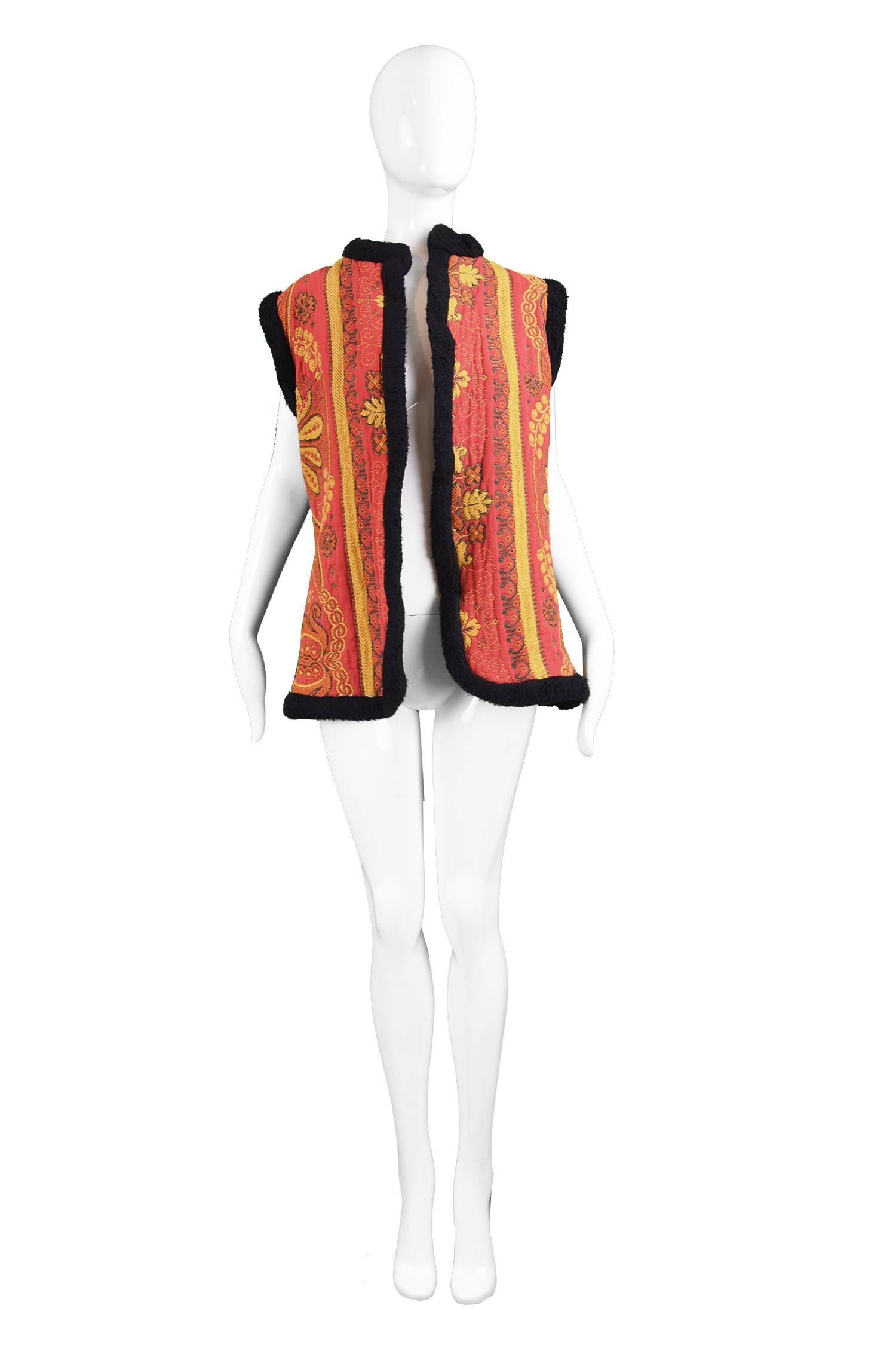 A bohemian vintage vest / waistcoat from the late 60s by British boutique label, Manon Maid of London. In a red floral tapestry fabric with a faux shearling trim around the sleeves and down the open front. In an afghan inspired style similar to the